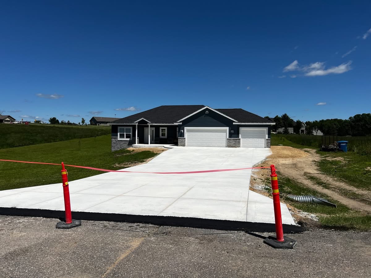 Finished concrete driveway and walkway in front of a gray ranch home